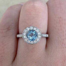 A charming cluster ring featuring a natural round aquamarine weighing 0.75 carats